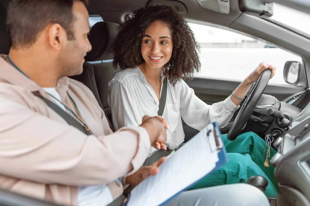 Une élève et son moniteur se serrent la main dans la voiture après la leçon