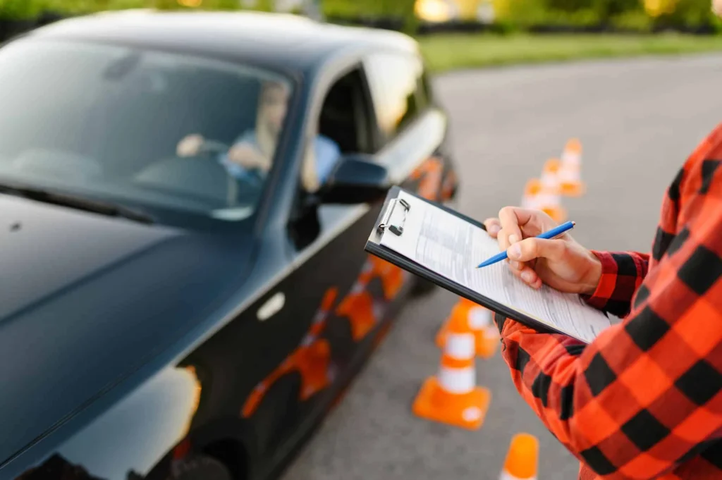 Moniteur avec une fiche d’évaluation à côté d’une élève au volant